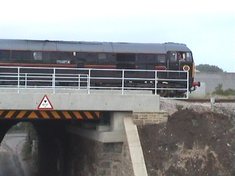 Train running over the bridge. New parapets installed.